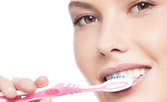 Image Of A Woman Brushing Her Teeth With A Pink Toothbrush